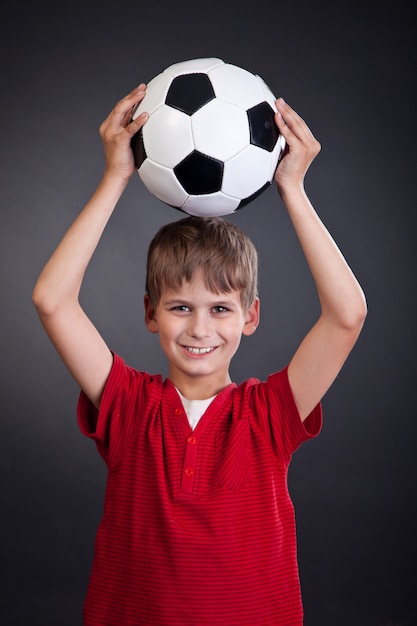 かわいい男の子がサッカーボールを保持しています。