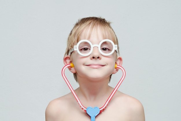 Cute boy is playing doctor. Toy glasses and phonendoscope. Portrait