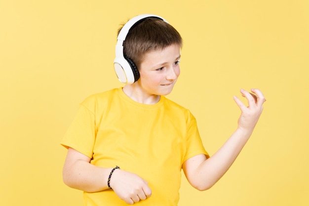 ヘッドフォンで音楽を聴いて、偽のまたは目に見えないギターを弾くかわいい男の子