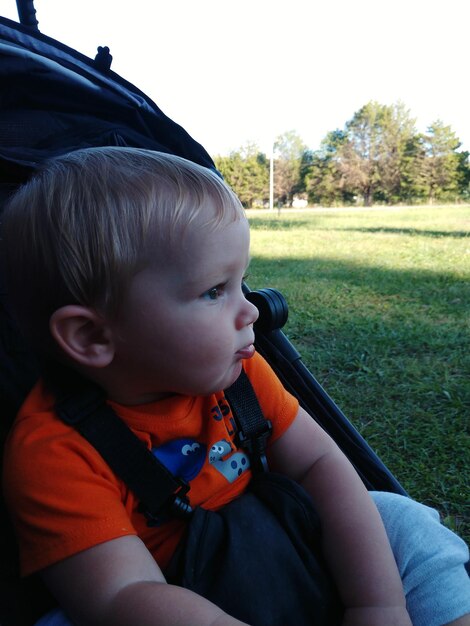 Cute boy looking away while sitting on car