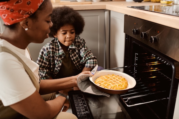 Cute boy looking at fresh hot apple by held by his mom