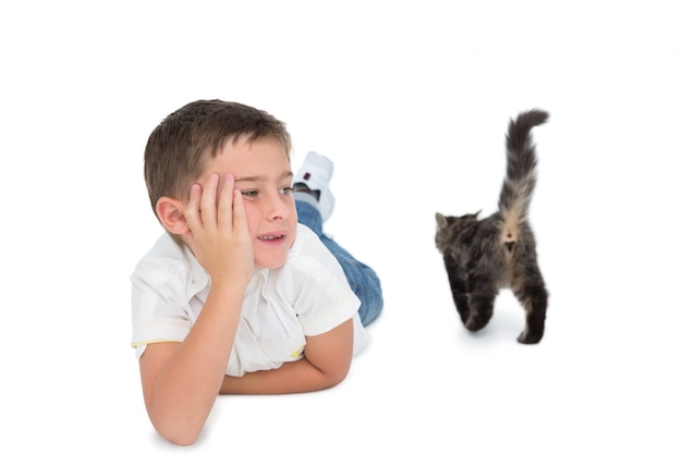 Cute boy looking at grey kitten lying on floor