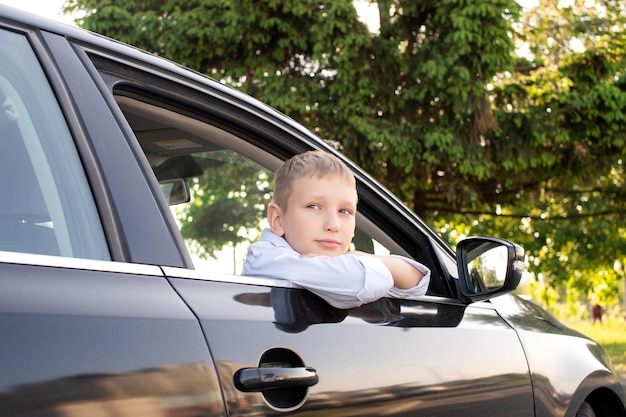 Photo a cute boy looks out the car window and is sad open car window long trip family day