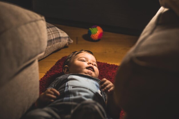 Photo cute boy lying down on carpet at home