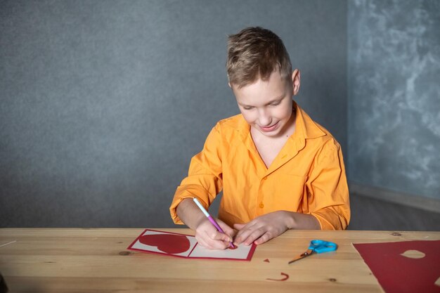 Cute boy makes a Valentine's day card with hearts