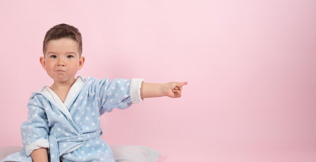 Cute boy on pink background points with his hand to the side photo for advertising product High quality photo