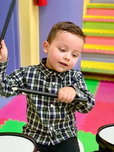 Photo cute boy playing drum kit at home