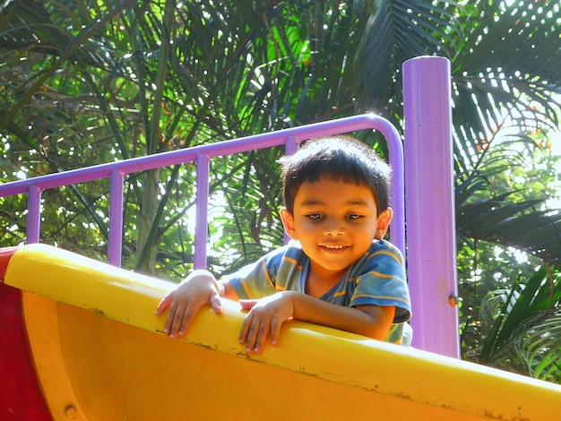 Cute boy playing on slide at playground