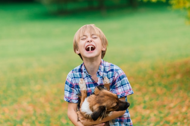 牧草地で犬と遊んだり歩いたりするかわいい男の子。