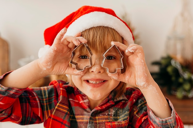 Cute boy playing with christmas cookie forms