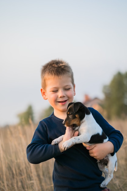 Cute boy playing with his dog in the meadow