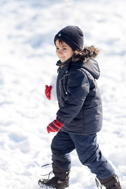 冬の公園で雪と遊ぶかわいい男の子