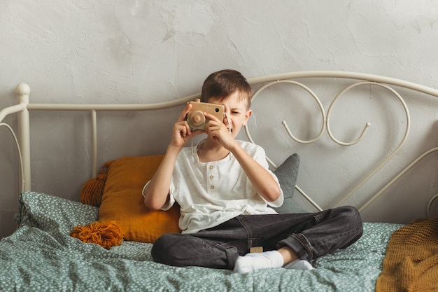 Cute boy plays photographer with toy wooden camera