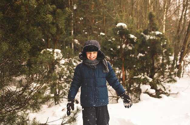 Cute boy plays with snow in a beautiful snow park in winter