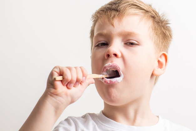 cute boy posing with bamboo toothbrush in his mouth, child brushes his teeth