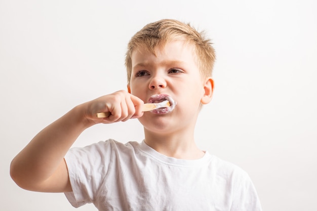 Photo cute boy posing with bamboo toothbrush in his mouth, child brushes his teeth