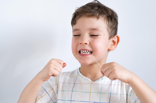 Cute boy pulling loose tooth using a dental floss process of removing a baby tooth