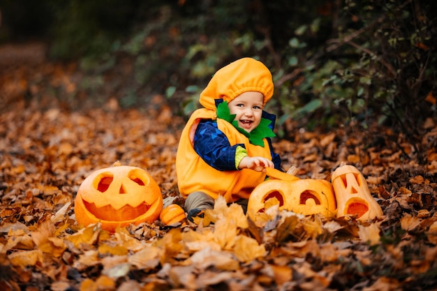 Ragazzo carino in costume da zucca tra zucche intagliate