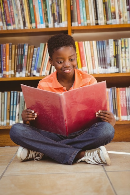 Cute boy reading book in library