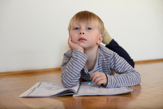 Ragazzo carino legge il libro sul pavimento a casa