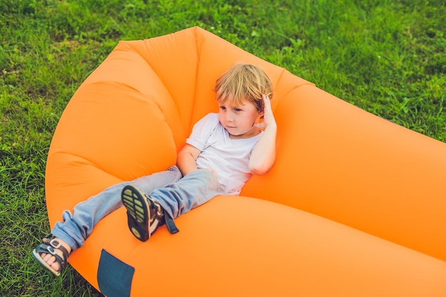 Cute boy resting on an air sofa in the park.. lamzac