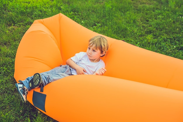 Cute boy resting on an air sofa in the park