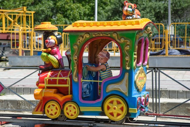 귀여운 소년은 어린이용 색깔의 기관차를 타고 철도를 탄다