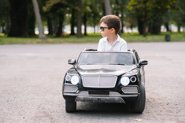 Cute boy in riding a black electric car in the park