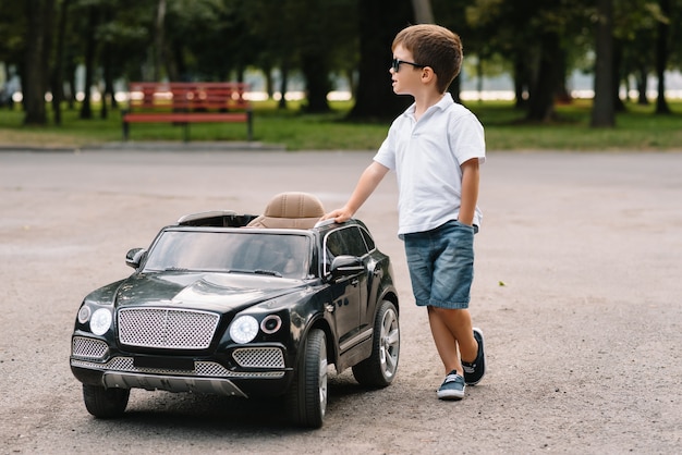 Ragazzo carino in sella a un'auto elettrica nera nel parco