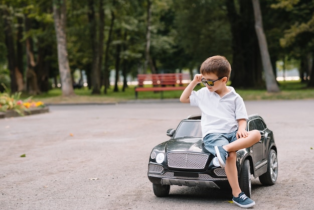 Cute boy in riding a black electric car in the park