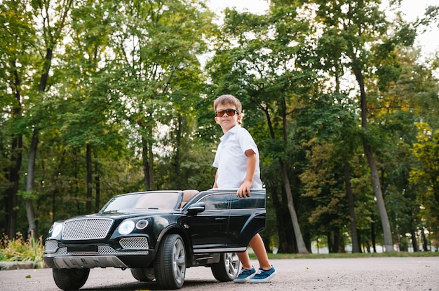 Ragazzo carino in sella a un'auto elettrica nera nel parco