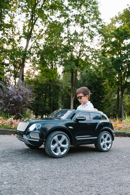 Cute boy in riding a black electric car in the park