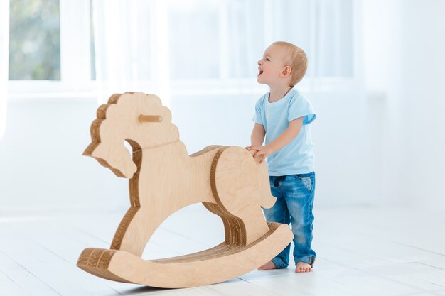 Милый мальчик качается на деревянной лошади ручной работы