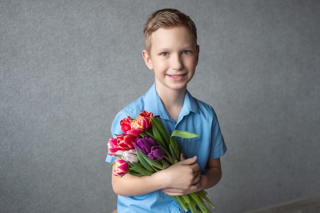 シャツを着たかわいい男の子がカラフルなチューリップの花束を手に持っているテキスト用のスペース