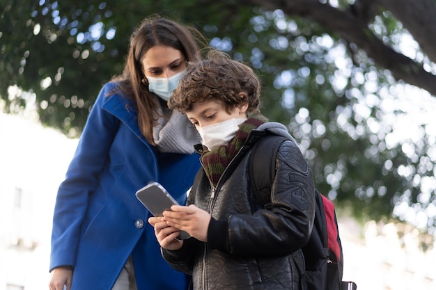 Cute boy showing how to use the smartphone to his mom Children addicted to mobile cell phone