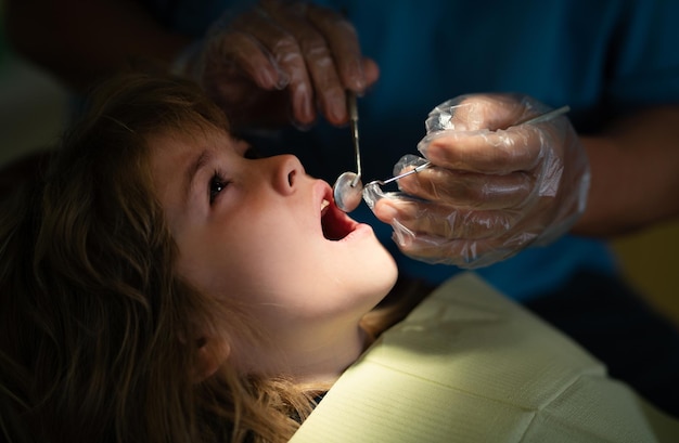 医師との口腔検査中に口を開けて歯科用の椅子に座っているかわいい男の子 訪問歯科医院 子供の口腔病学 口腔子供の空洞