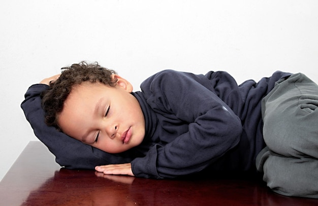 Photo cute boy sleeping on wood against white background