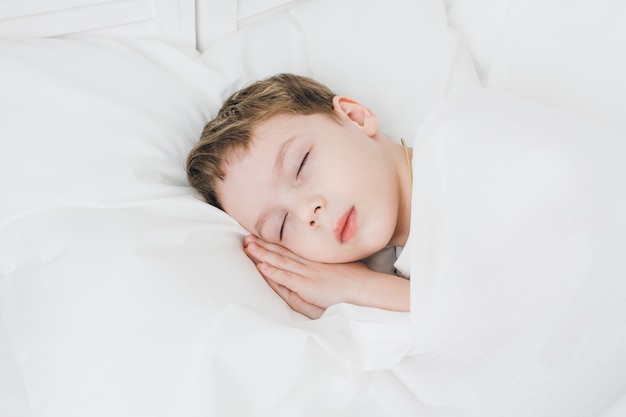 Il ragazzo sveglio dorme di mattina a letto