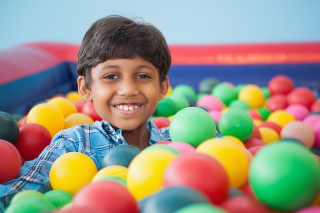Симпатичный мальчик, улыбаясь в мяч бассейн