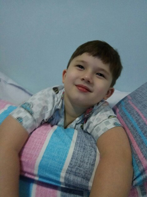Cute boy smiling while lying on bed