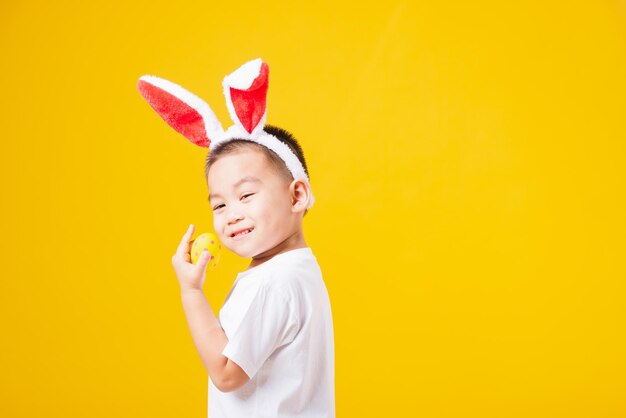 Cute boy standing against yellow background