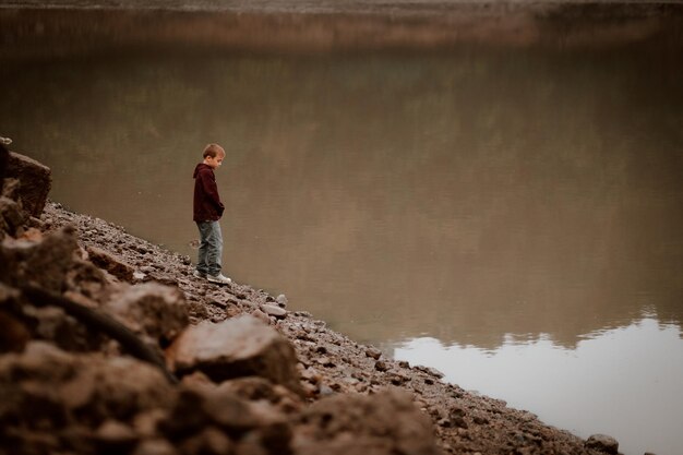 Photo cute boy standing by lake