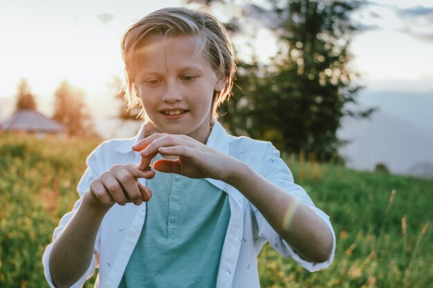 Photo cute boy standing by plants against tree and sky