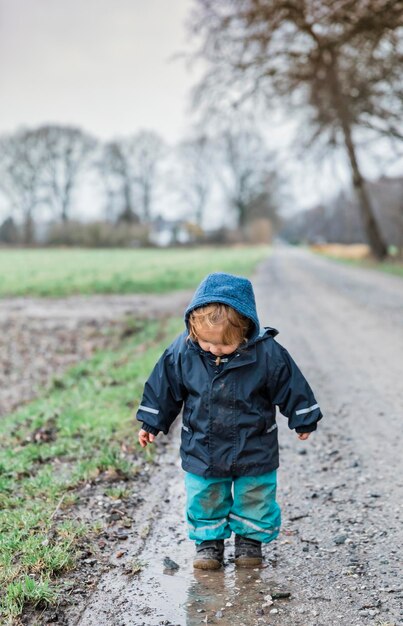 Photo cute boy standing on dirt road