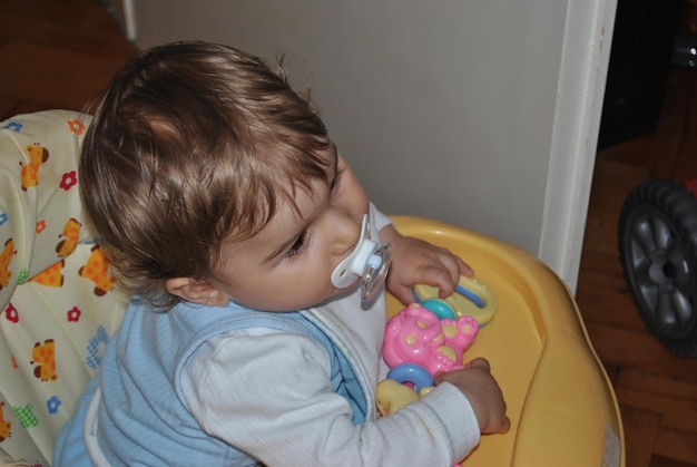 Foto un ragazzo carino che succhia il ciuccio in un passeggino a casa.