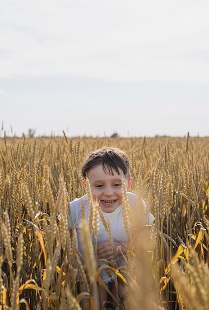 Ragazzo carino che cammina attraverso il campo di grano facendo facce buffe