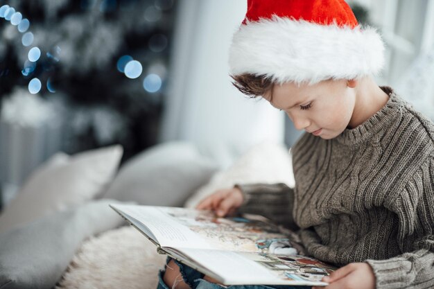 Foto un ragazzo carino che indossa un cappello che legge un libro a casa.