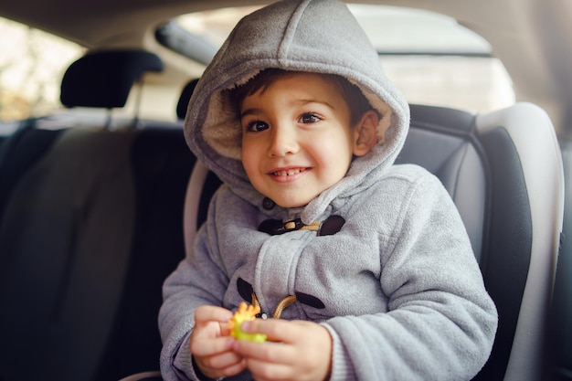 cute boy wearing hood sitting at car