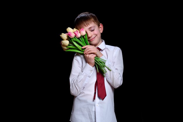 Cute boy in white shirt with a bouquet of tulips.