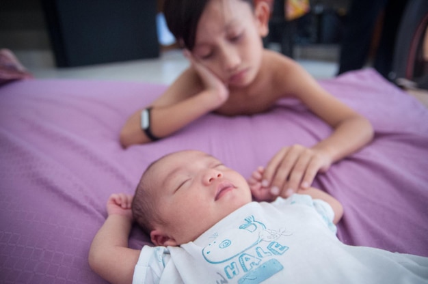 Photo cute boy with baby girl on bed at home